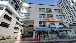 Un immeuble à plusieurs étages abritant un magasin 7-Eleven au rez-de-chaussée, avec une entrée bien visible et un vélo garé à l’extérieur.