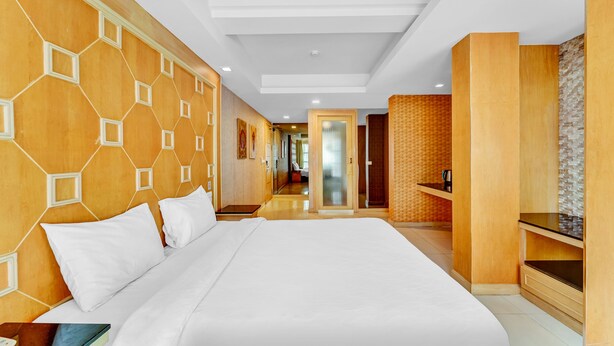 Une chambre d’hôtel moderne avec un grand lit, des panneaux de bois et une vue sur le couloir.
