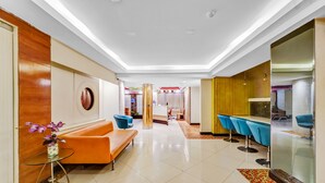 Un hall d’hôtel moderne comprenant un comptoir d’accueil, un espace salon et un bar.