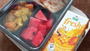 Un repas composé d’un récipient en verre, d’une boîte de jus de fruits tropicaux frais de la marque Unif et d’un morceau de pain plat.