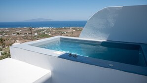 A white infinity pool with a clear view of the sea and distant land.