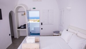 A hotel room with a bed, a desk, and a view of the sea.