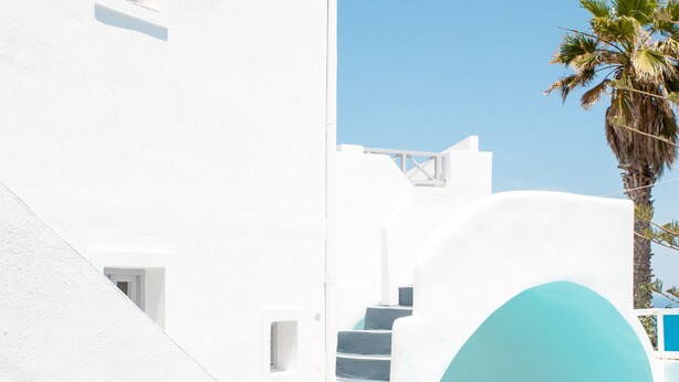 A white building with a blue pool and stairs leading to an entrance.