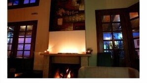 A room with a fireplace, a large window with a view, and a painting on the wall. - Astromeria Hotel (Zagora-Mouresi)