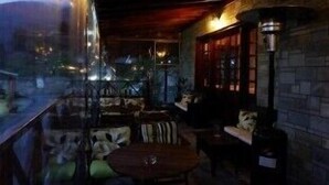 An indoor seating area with tables and chairs, a brick wall, and a window with a view of the outside. - Astromeria Hotel (Zagora-Mouresi)