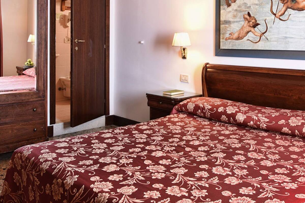 Une chambre d’hôtel avec un lit, une porte en bois, un tableau et une table de chevet.