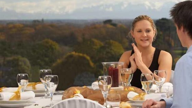 A dining table set with plates, glasses, and a bottle, overlooking a scenic landscape. - Tarconte (Tarquinia)