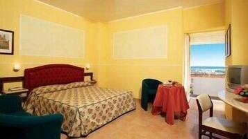 Habitación de hotel con cama, escritorio, silla y vista al mar.
