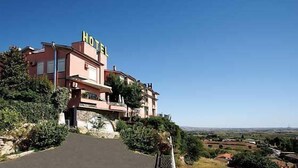 A hotel with a prominent 'HOTEL' sign, a stone facade, and a view of the surrounding countryside. - Tarconte (Tarquinia)