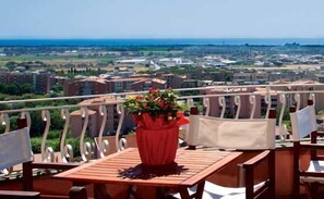 A balcony with a table and chairs, a potted plant, and a view of a cityscape. - Tarconte (Tarquinia)