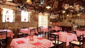 A restaurant with checkered tablecloths, wooden chairs, and stone walls. - Tarconte (Tarquinia)
