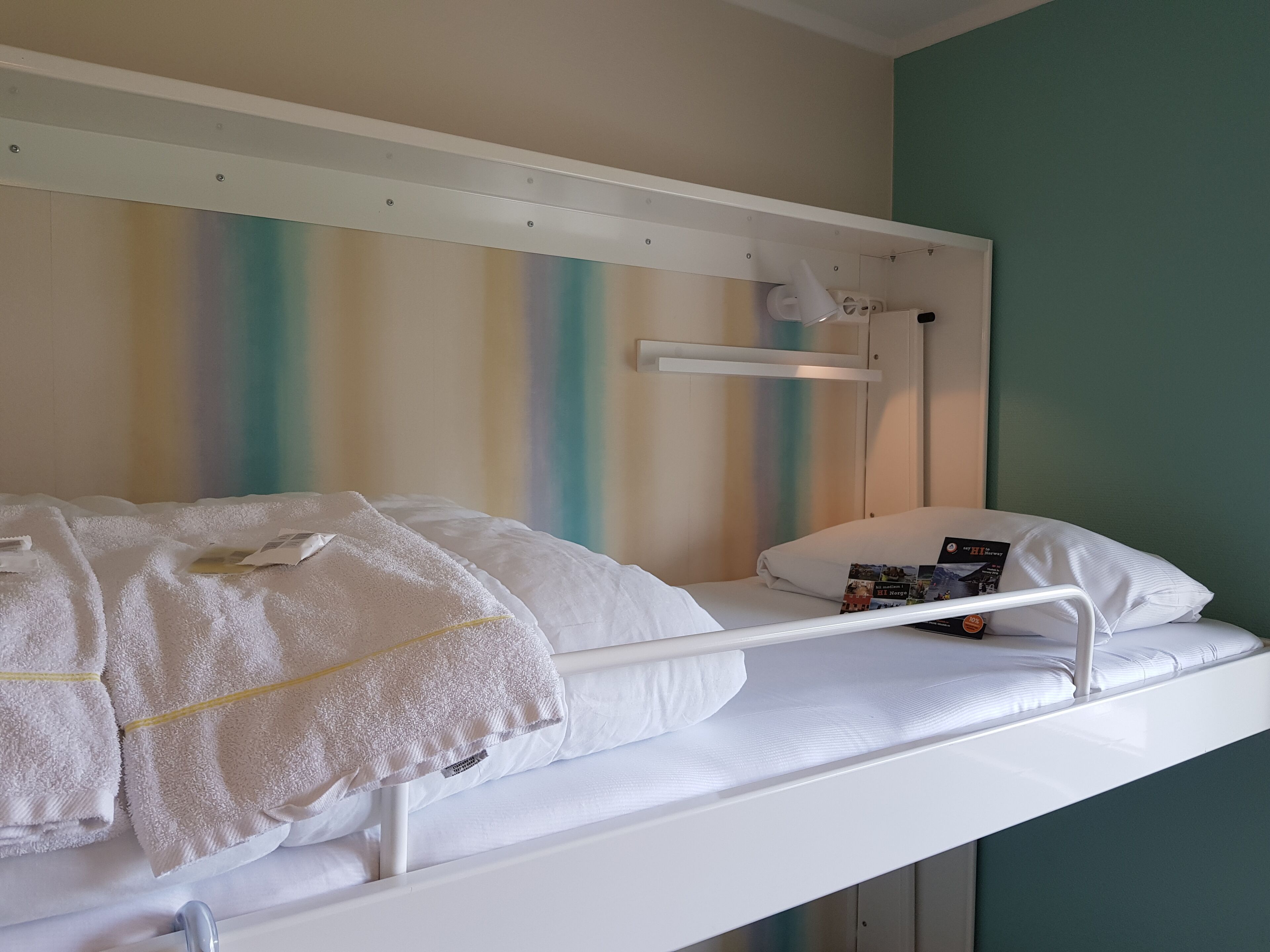 A bunk bed with white bedding and a small table with magazines.