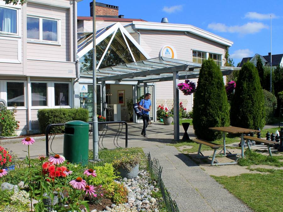 A building with a covered entrance, a green trash bin, and outdoor seating.