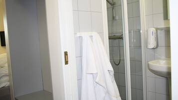 A bathroom with a shower, a sink, and a towel rack.