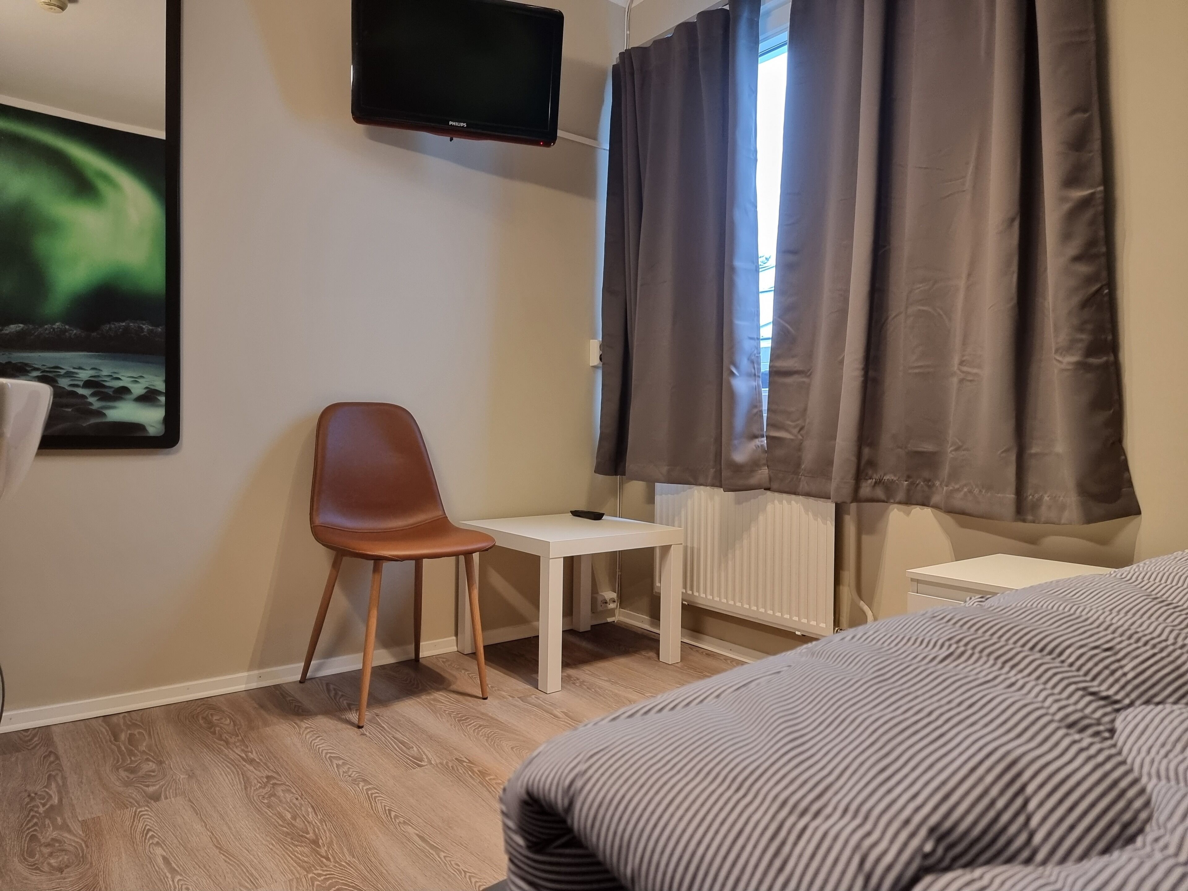 A hotel room with a bed, a desk, a chair, a television, and a window with curtains.