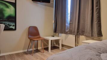 A hotel room with a bed, a desk, a chair, a television, and a window with curtains.