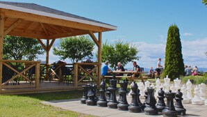 A wooden pavilion with a tiled roof, surrounded by chess pieces and outdoor seating. - HI Oslo Haraldsheim - Hostel (Oslo)
