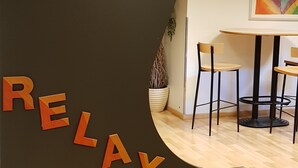 A reception desk with a 'RELAX' sign, a potted plant, and a table with chairs in a modern interior. - HI Oslo Haraldsheim - Hostel (Oslo)