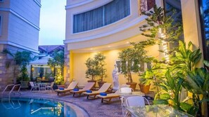 A poolside area with lounge chairs, potted plants, and a statue. - Four Seasons Place (Pattaya)