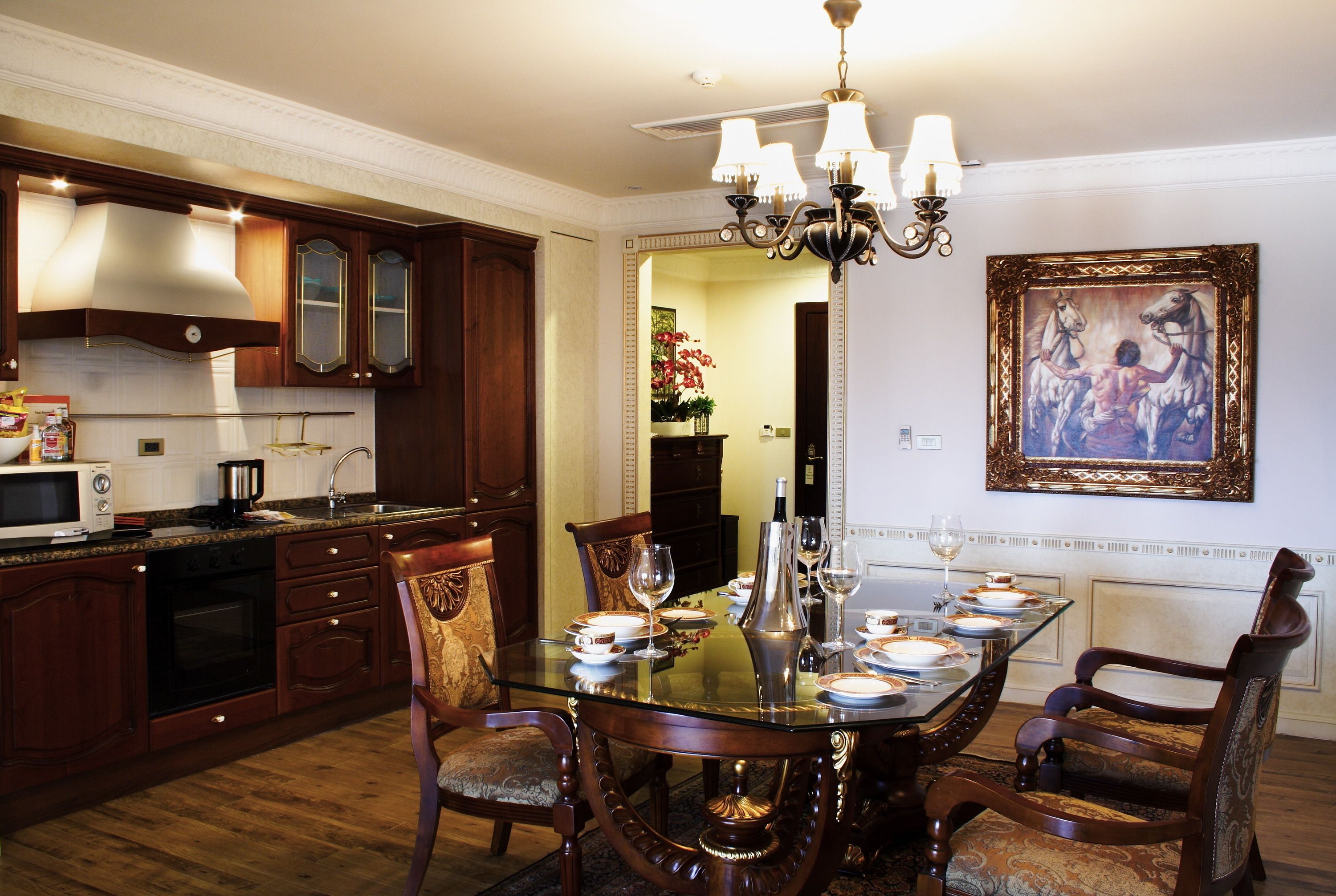 A dining area with a glass table, wooden chairs, and a chandelier.