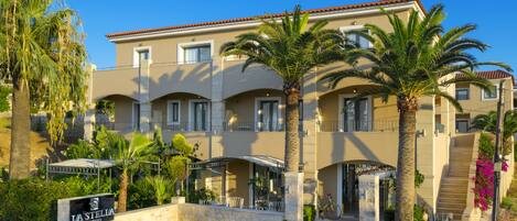A hotel with a stone facade, multiple balconies, and palm trees.