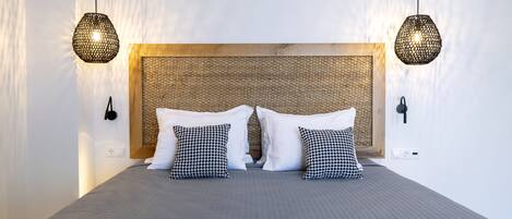 A modern bedroom with a large bed, two hanging light fixtures, and a textured headboard.