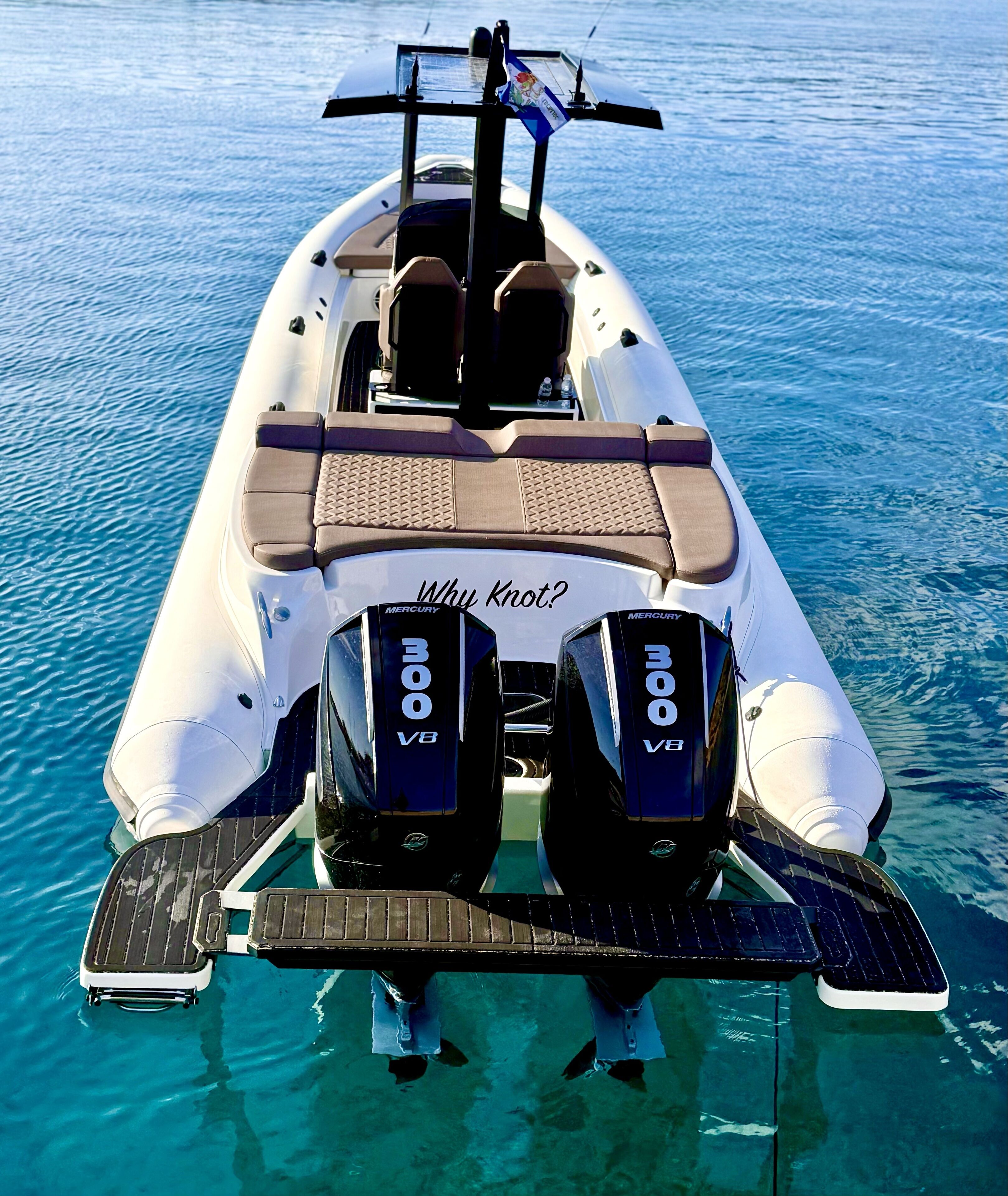 Un bateau équipé de deux moteurs Mercury V8, d’un espace salon avec des coussins et d’une pancarte sur laquelle on peut lire « Why Knot? »