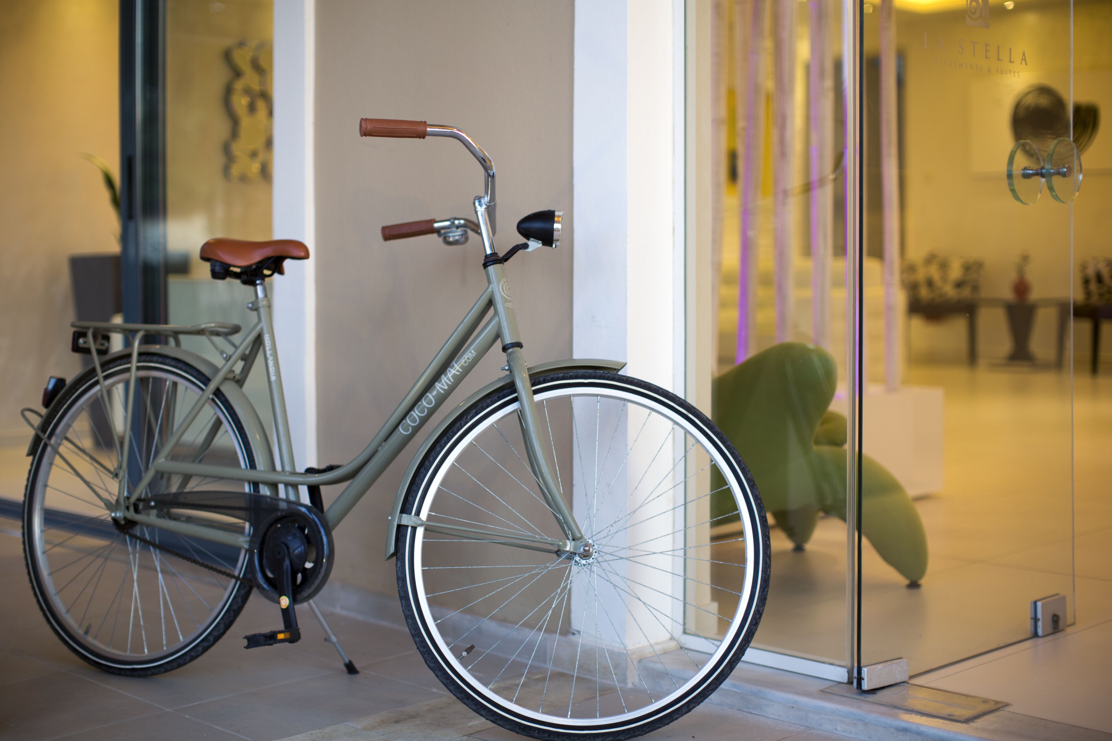 A stationary bicycle with a brown seat and a silver frame, positioned indoors near a glass door.