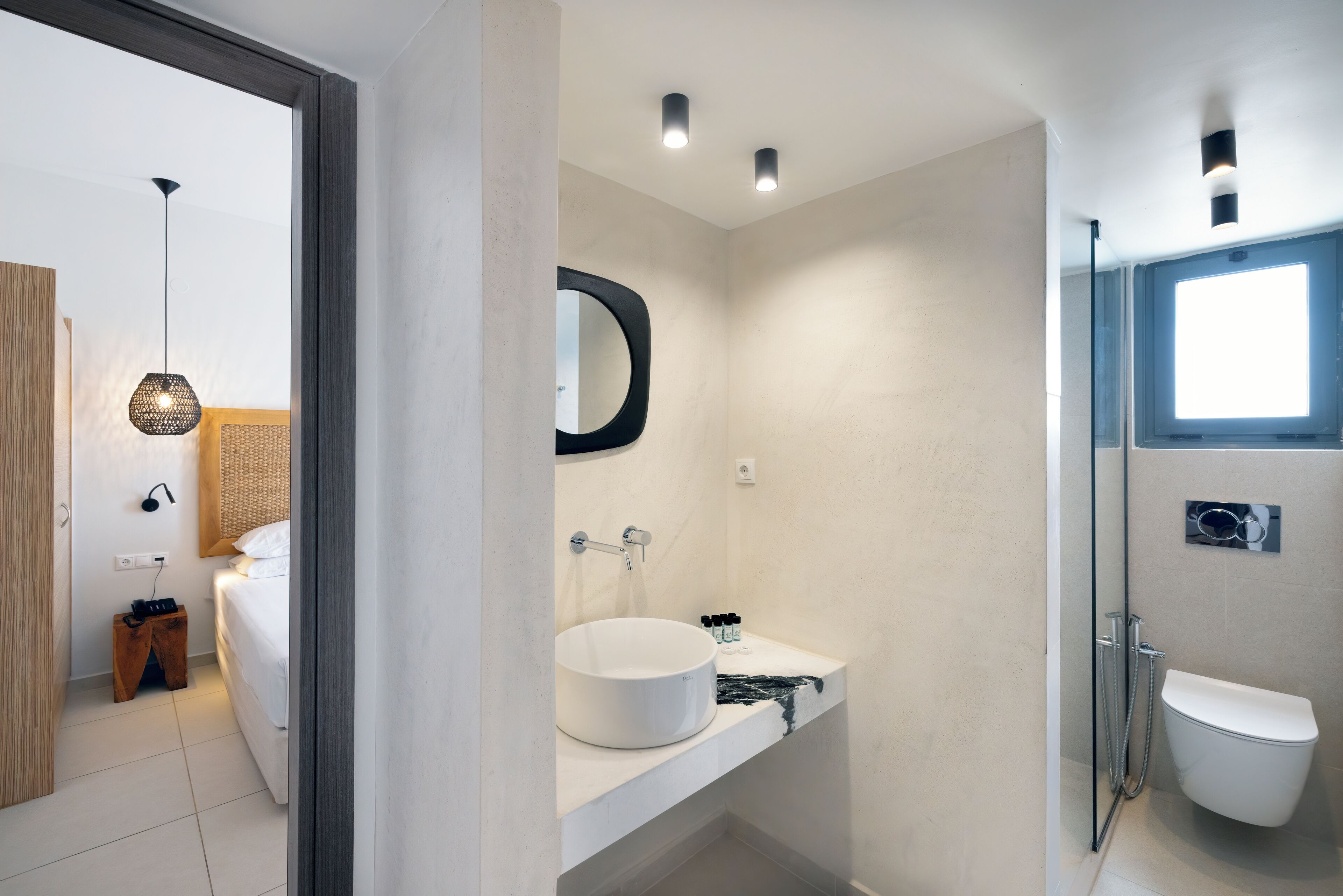A modern bathroom with a round sink, a toilet, and a shower.