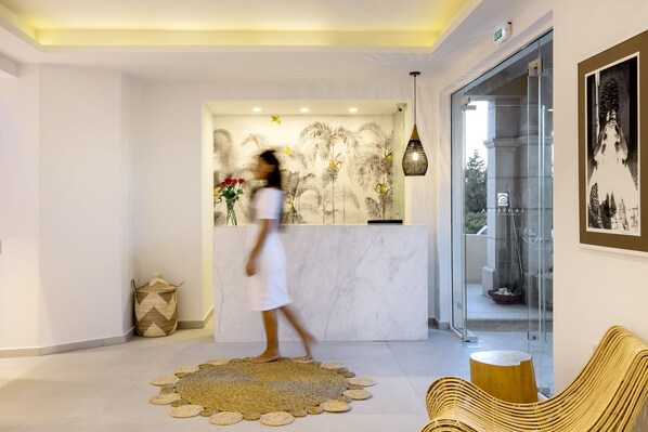 A modern lobby with a reception desk, a woven rug, and wicker furniture.