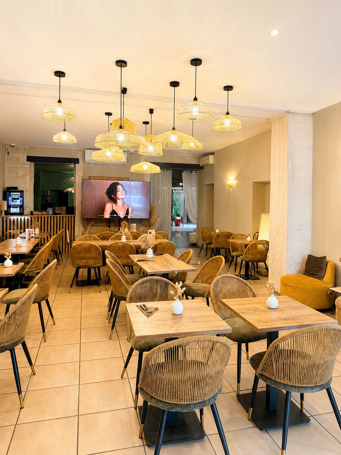 Un restaurant doté de nombreuses tables et chaises, d’un écran de télévision et de luminaires suspendus.