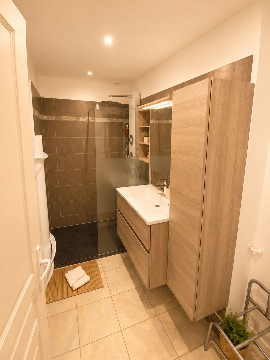 A modern bathroom with a glass shower enclosure, a wooden vanity, and a mirror cabinet.