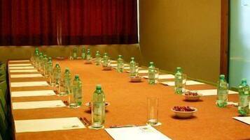A conference room with a long table set for a meeting, equipped with water bottles, glasses, and a bowl of fruit.
