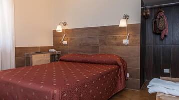 A hotel room with a bed, bedside lamps, a wooden desk, and a wardrobe.