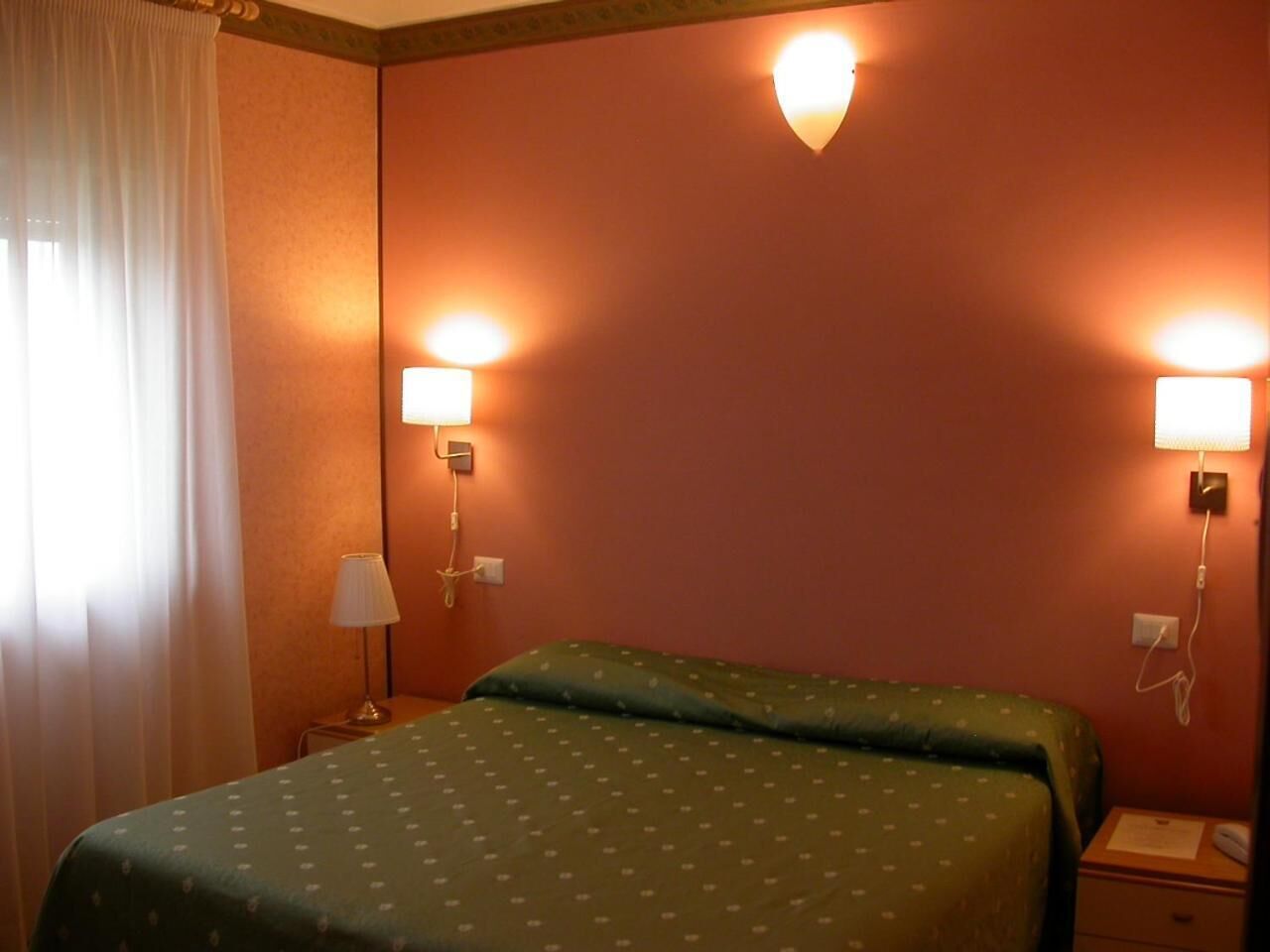 Een hotelkamer met een bed, twee bedlampen en een telefoon.