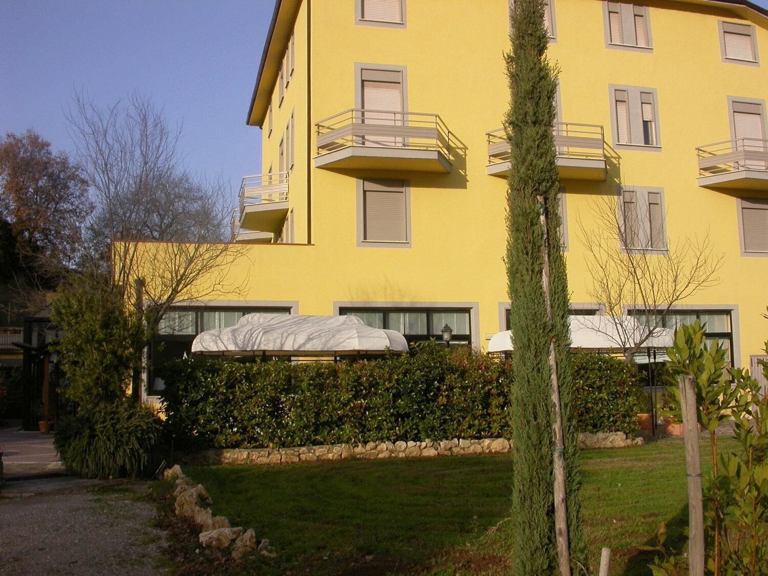 Ein gelbes Gebäude mit mehreren Balkonen und einem gepflegten Garten.