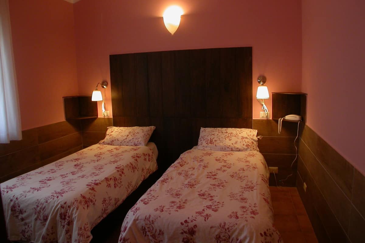 A hotel room with two beds, each with floral bedding, a dark headboard, and bedside lamps.