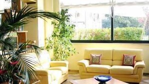 Un salón con un sofá amarillo, una mesa de centro y un ventanal con vistas al verdor.