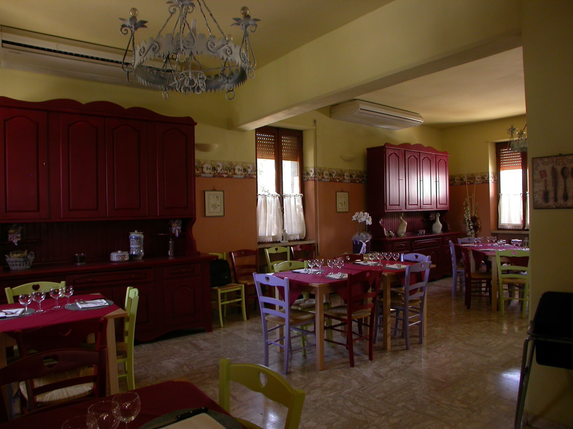 A dining area with red wooden cabinets, a chandelier, and a table set for a meal.