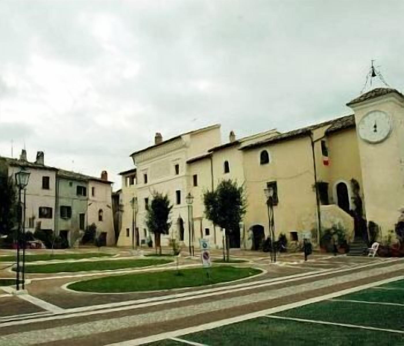 Un bâtiment doté d’une tour horlogée, d’une cour avec une fontaine et d’un chemin piétonnier dallé.