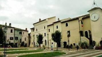 Un bâtiment doté d’une tour horlogée, d’une cour avec une fontaine et d’un chemin piétonnier dallé.