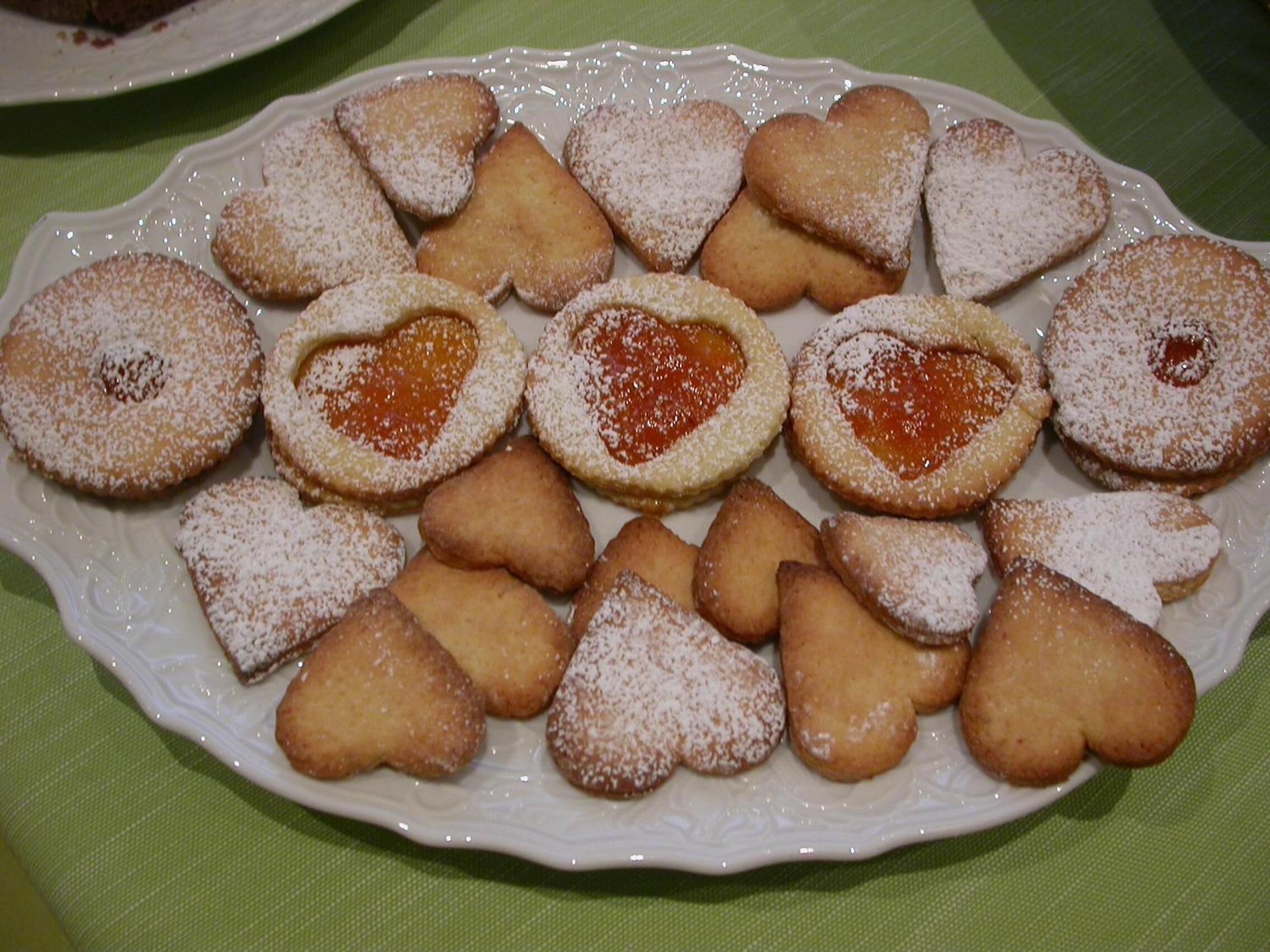 Ein Teller mit herzförmigen Plätzchen bestreut mit Puderzucker.