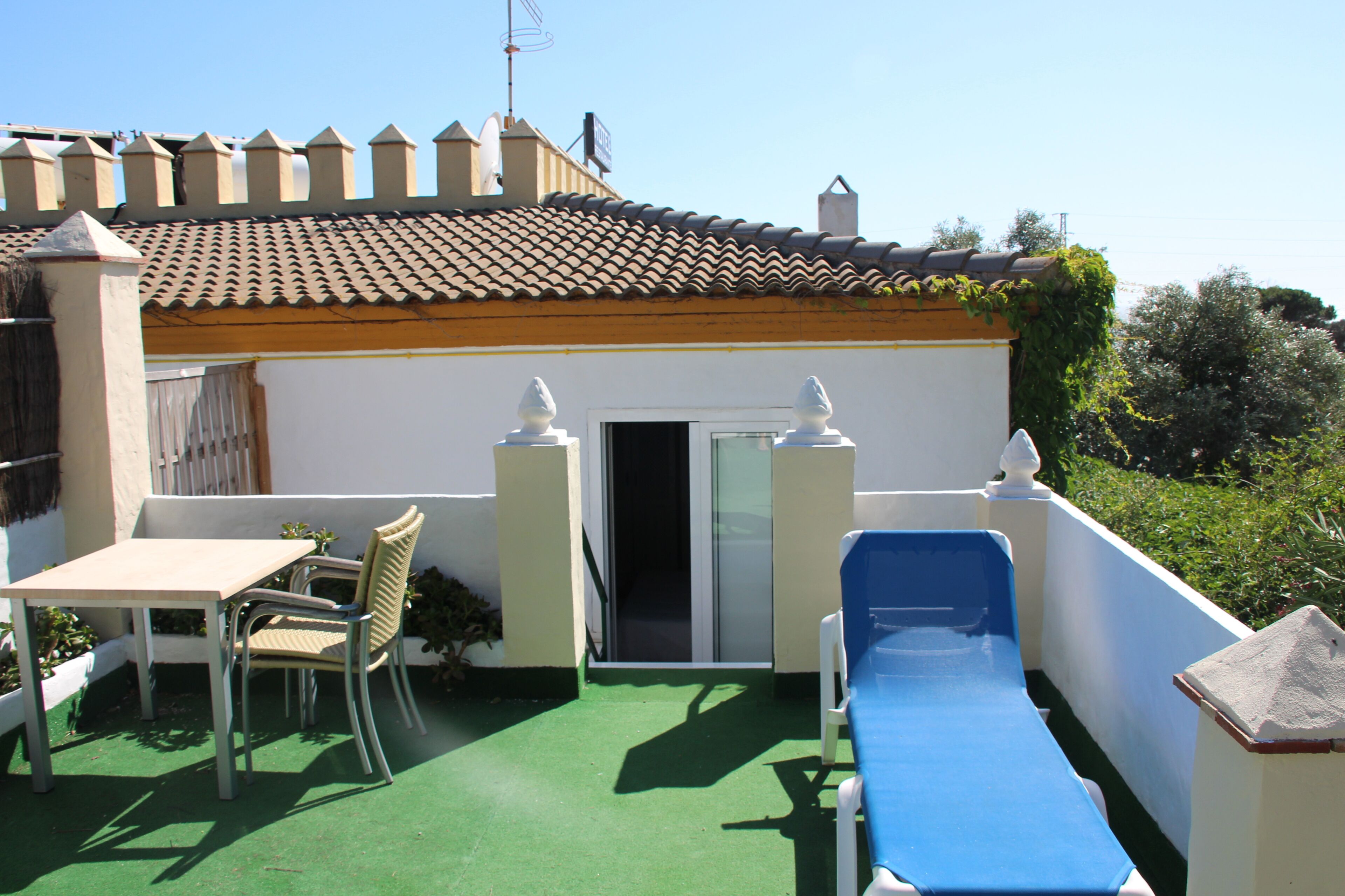 Une terrasse sur le toit, avec une table, des chaises et un transat.