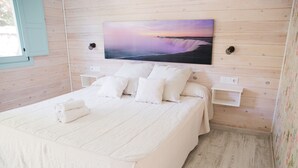A bedroom with a bed, pillows, a nightstand, and a wall-mounted painting. - La Torre (Tarifa)