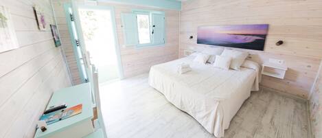A bedroom with a bed, a TV mounted on the wall, and a desk with a chair.