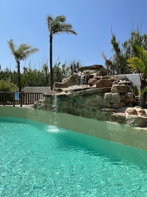 Una piscina al aire libre de temporada, sombrillas