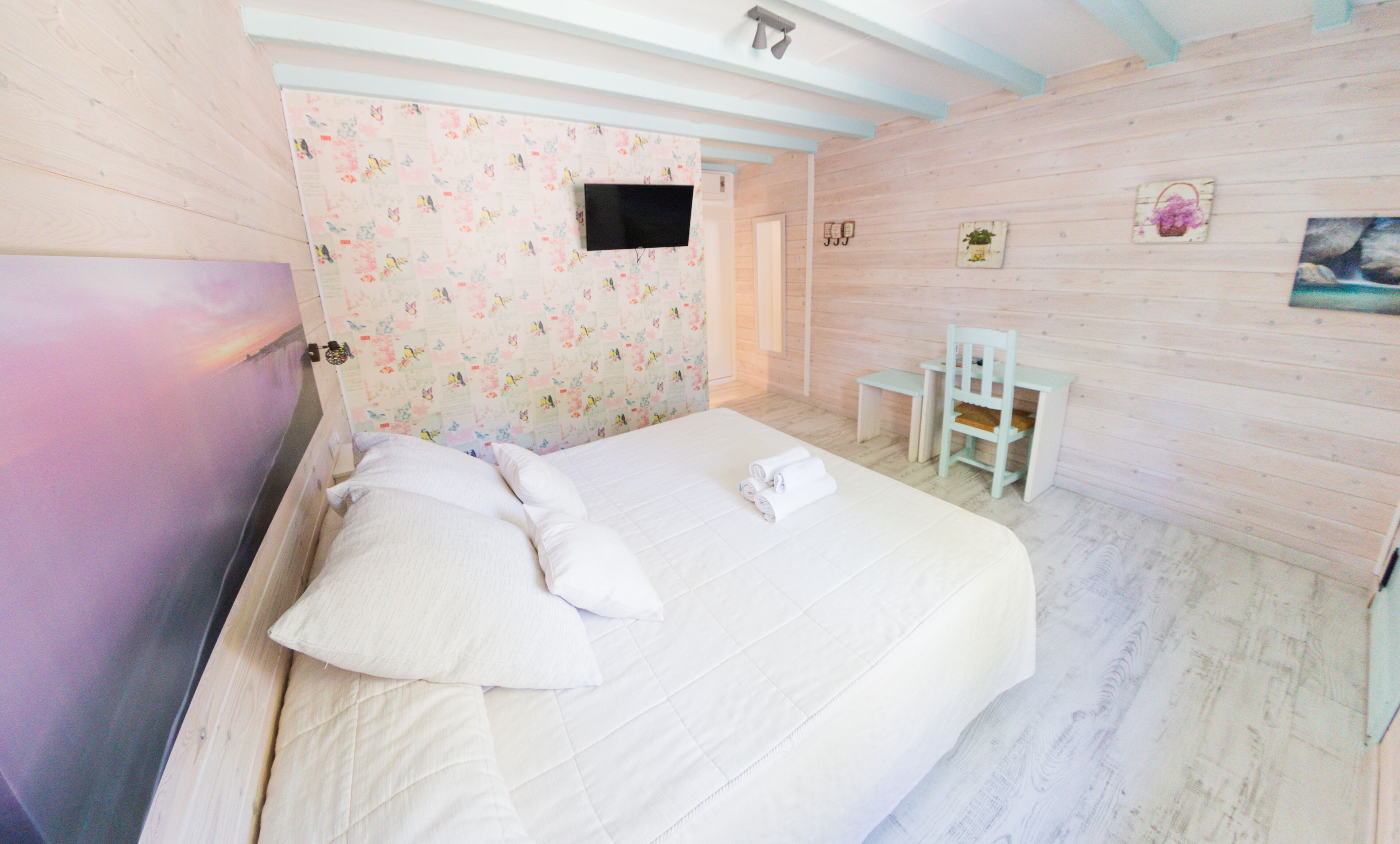 A bedroom with a bed, a desk, and a chair.