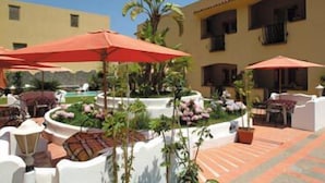 Un patio con mobiliario exterior, piscina y palmeras.