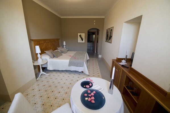 A small, neatly arranged bedroom with a bed, bedside table, and a small round table with a candle and a sign. - Modà Antica Dimora (Montegiardino)