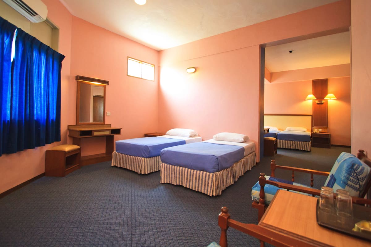 A hotel room with two beds, a desk, a chair, a mirror, and a window with curtains.